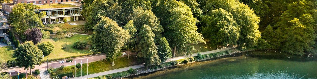 Das Bild zeigt den See und dahinter die Klinik Buchenholm. 