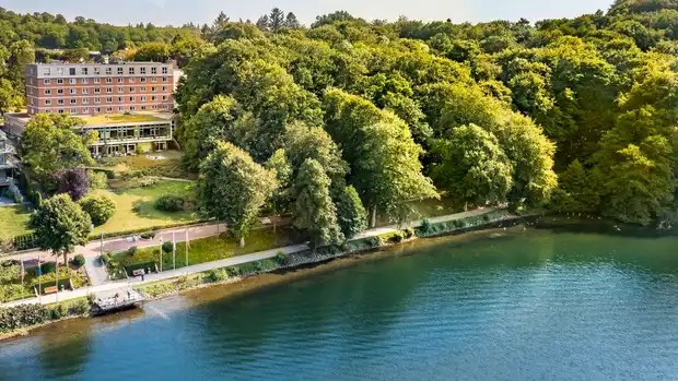 Das Bild zeigt den See und dahinter die Klinik Buchenholm. 