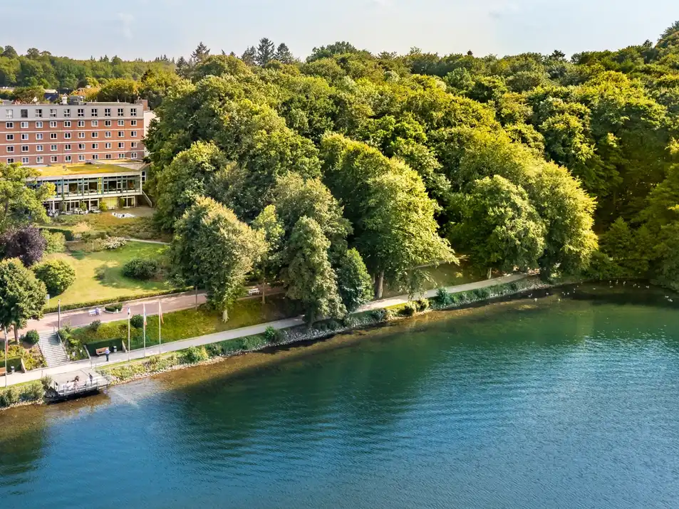 Das Bild zeigt den See und dahinter die Klinik Buchenholm. 